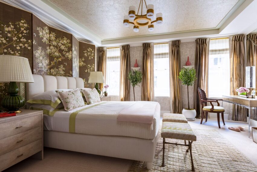 Luxurious bedroom with floral wallpaper, elegant bedding, cushioned bench, large windows, and modern chandelier.