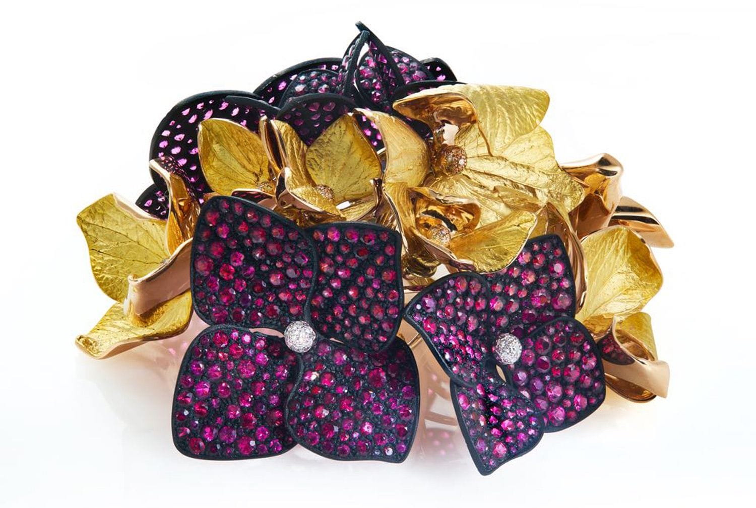 Intricate flower-shaped jewelry piece with gold and purple petals, adorned with sparkling gemstones.