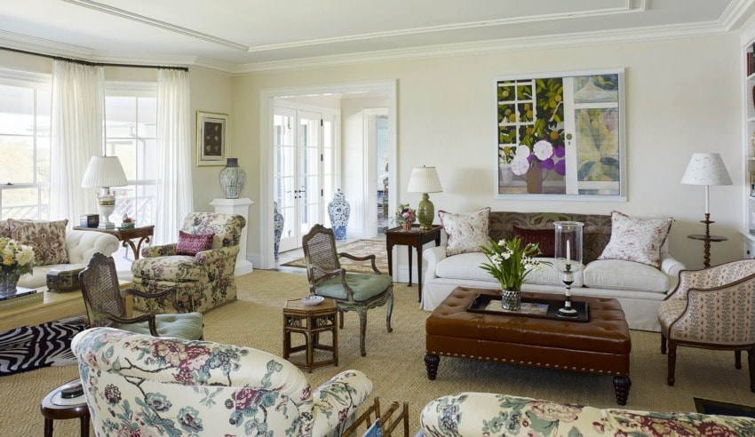Bright living room with floral-patterned sofas, a leather ottoman, and colorful artwork on the wall.