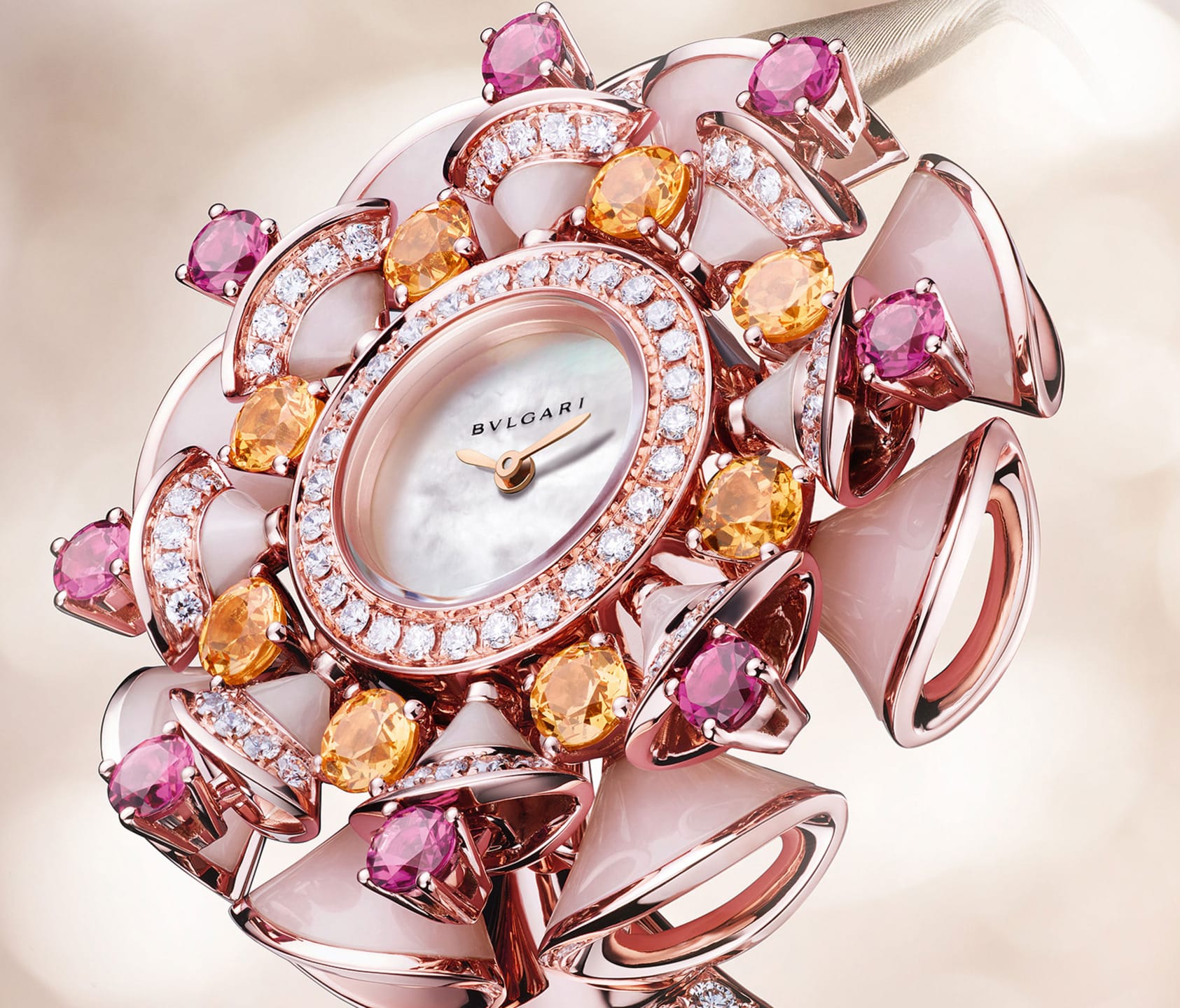 Luxurious rose gold watch adorned with pink, orange gemstones, and a mother-of-pearl face, set against a soft background.
