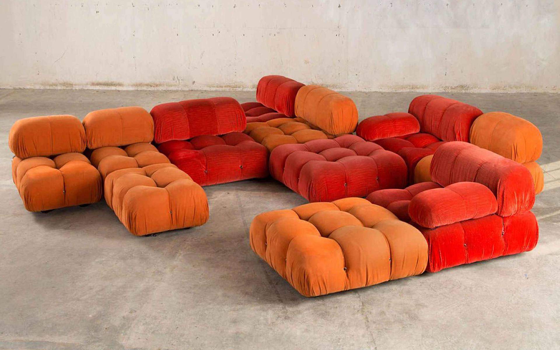 Modular orange and red bubble couches arranged in a large, open concrete room.