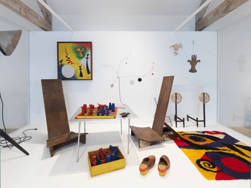 Modern art exhibit featuring abstract sculptures, colorful paintings, and playful furniture arranged in a bright gallery space.