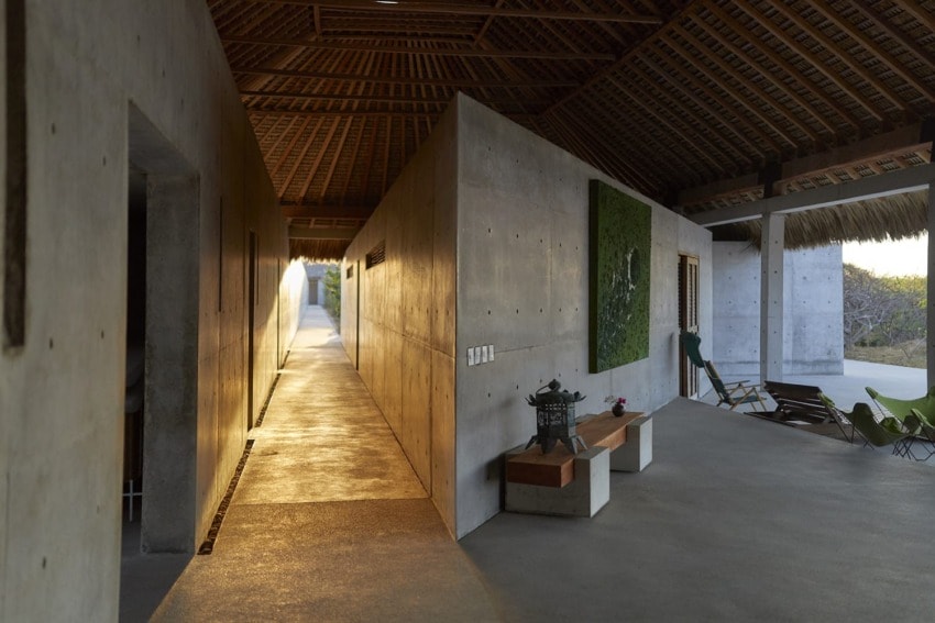 Modern concrete hallway with wooden ceiling and outdoor seating area in evening light