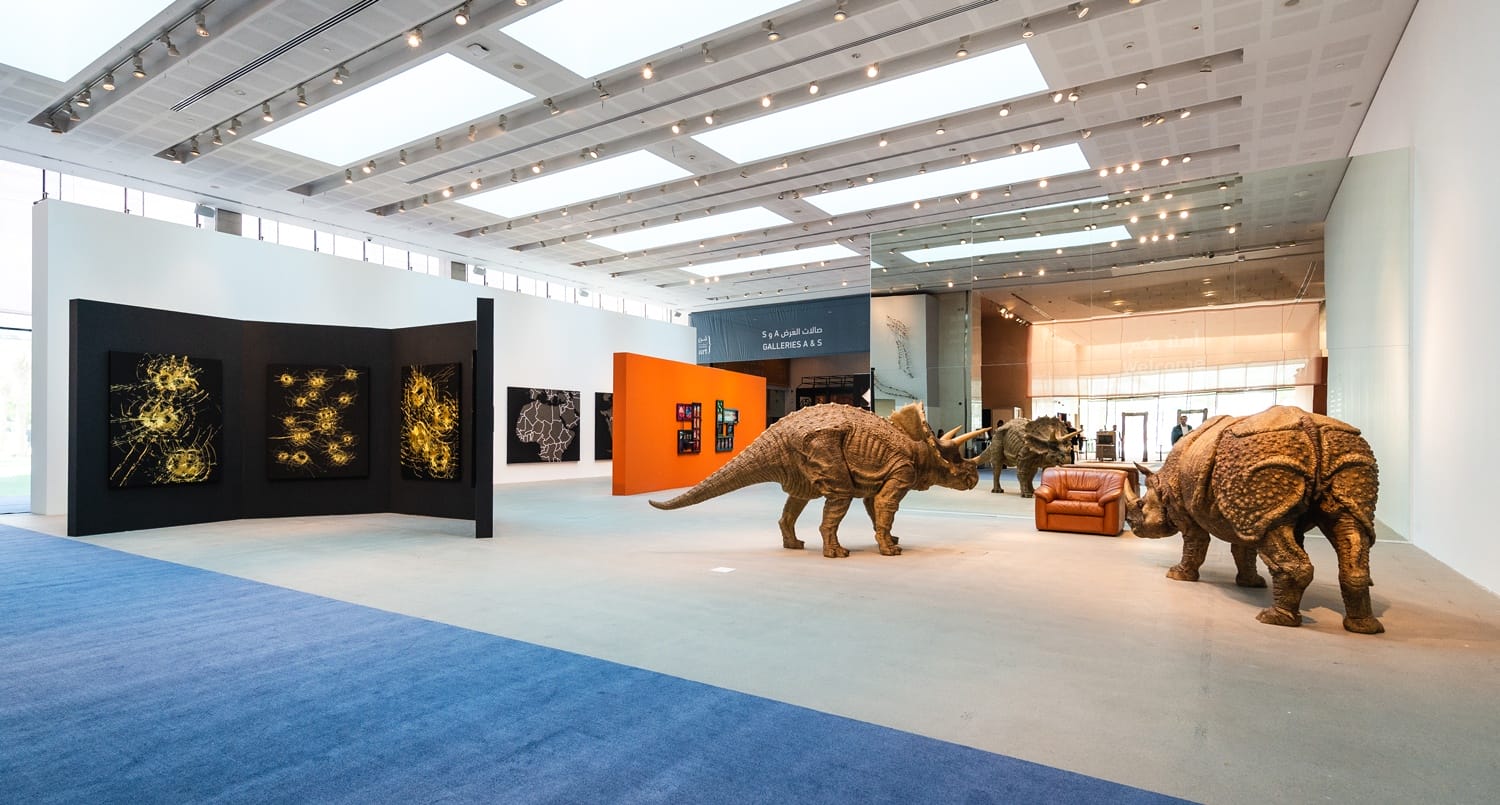 Art gallery with dinosaur sculptures and abstract wall art, featuring large windows and modern architectural design.