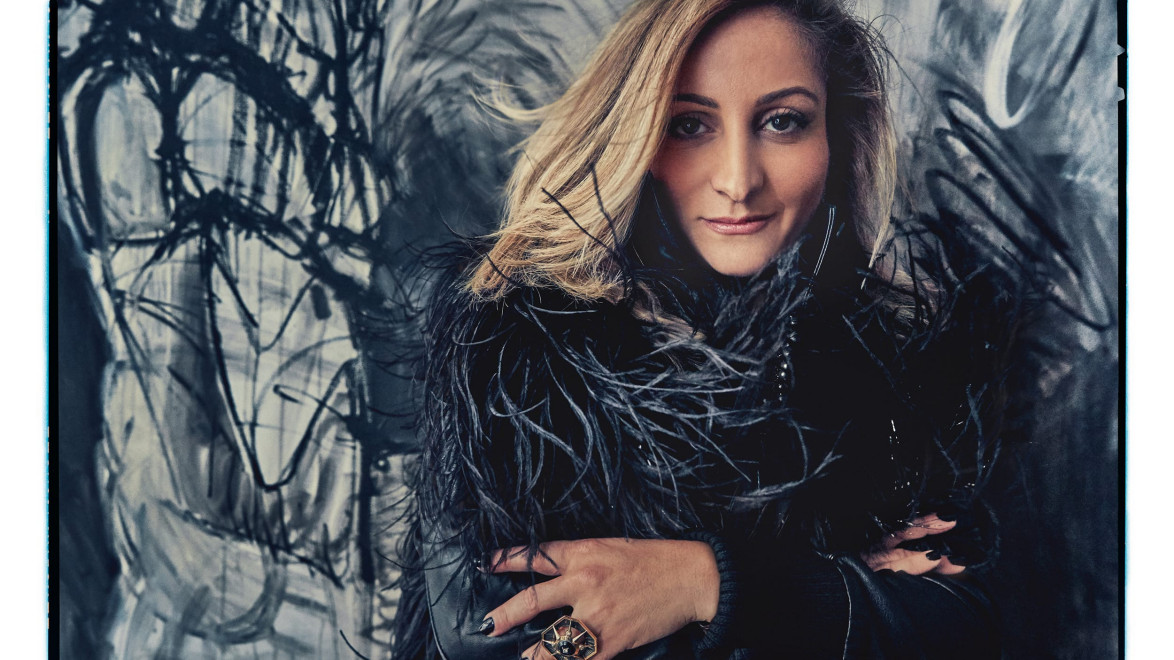 Person in a feathered jacket standing in front of abstract black and gray art.