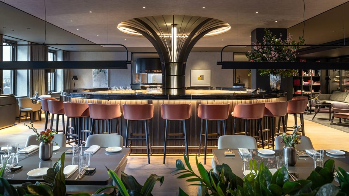 Modern restaurant interior with a circular bar, elegant lighting, and neatly arranged tables and chairs.