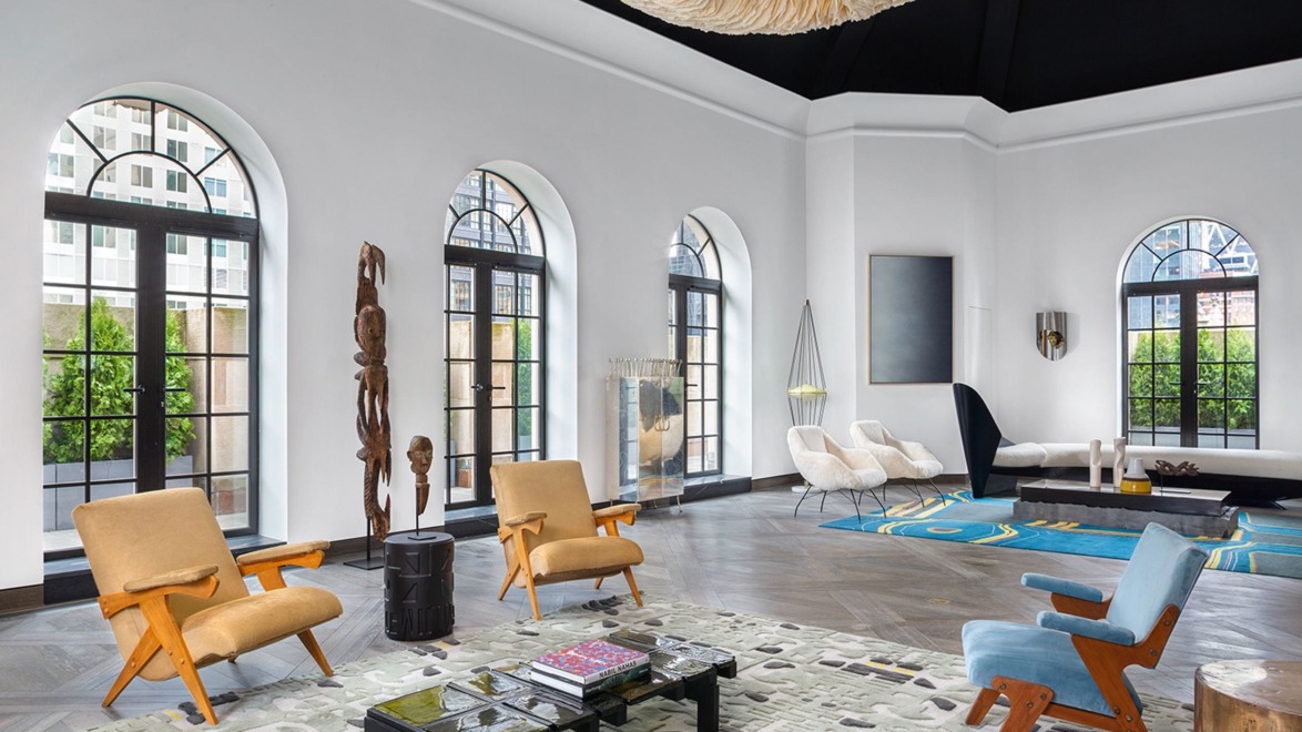 Modern living room with arched windows, stylish furniture, abstract rug, and unique ceiling fixture.