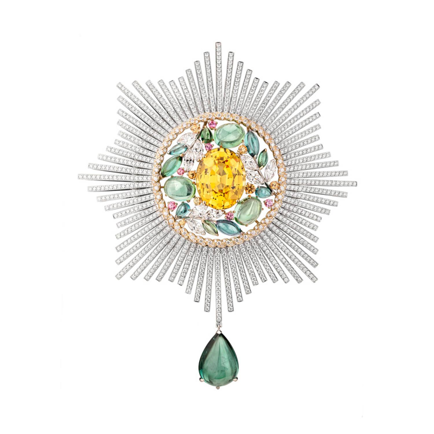 Intricate sunburst brooch with a large yellow gemstone center, surrounded by diamonds and a teardrop green gem pendant.