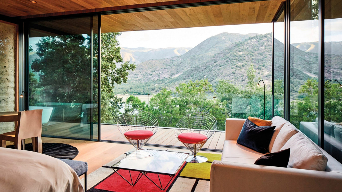 modern living room with glass walls offering a panoramic mountain view