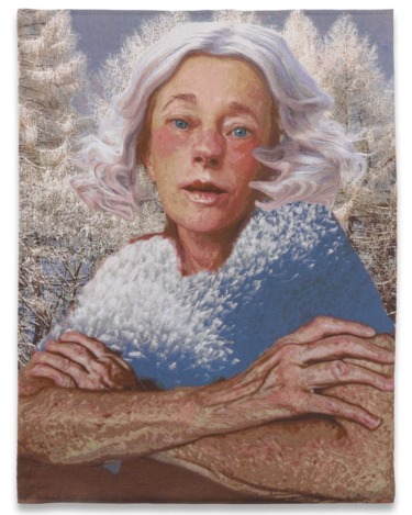 Portrait of an older person with white hair, arms crossed, wearing a textured shawl, set against a snowy forest backdrop.