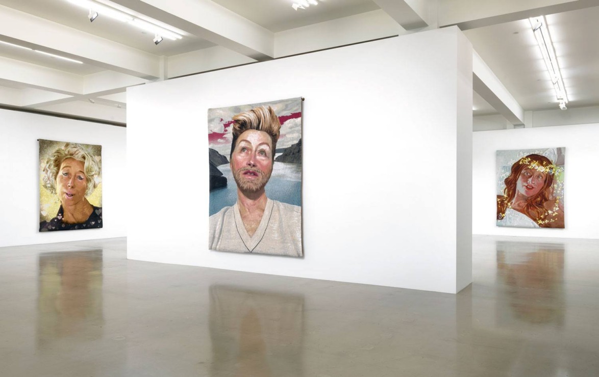 Art gallery with three portrait paintings displayed on white walls in a modern, well-lit exhibition space.