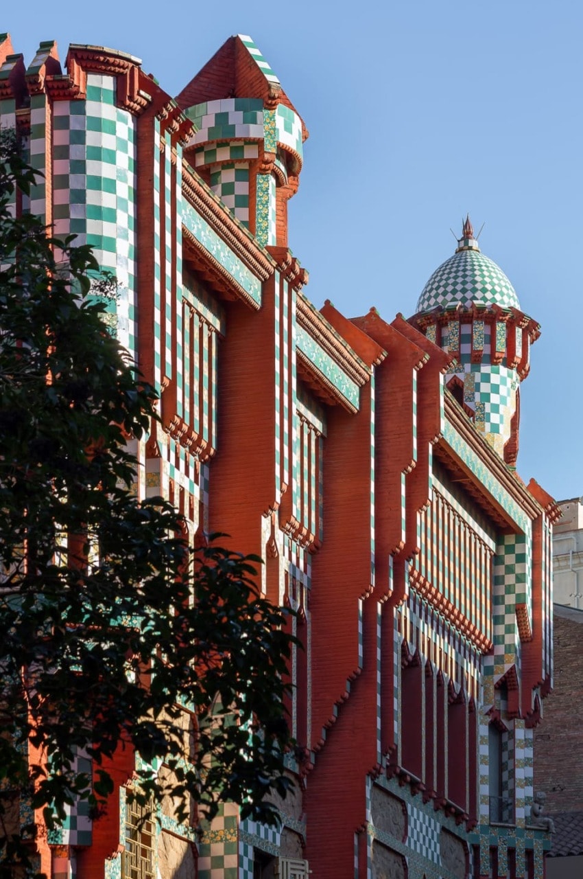 Colorful facade of Casa Vicens with intricate geometric patterns and vibrant red, green, and white tiles under a clear sky.