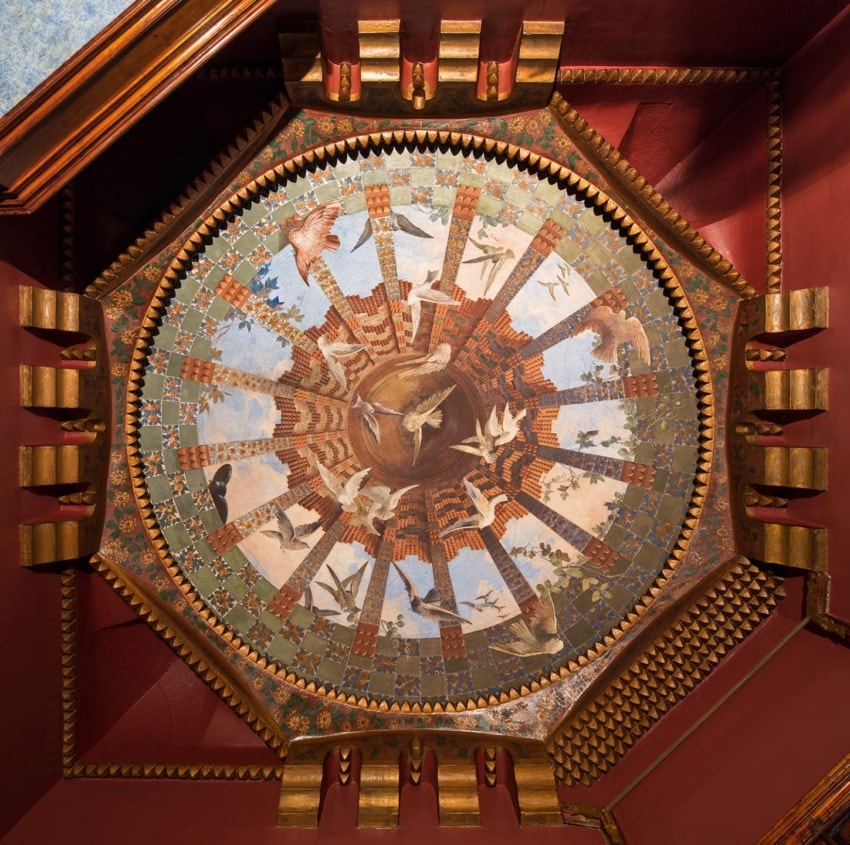 Ornate ceiling mural featuring various birds in flight surrounded by intricate geometric and architectural patterns.