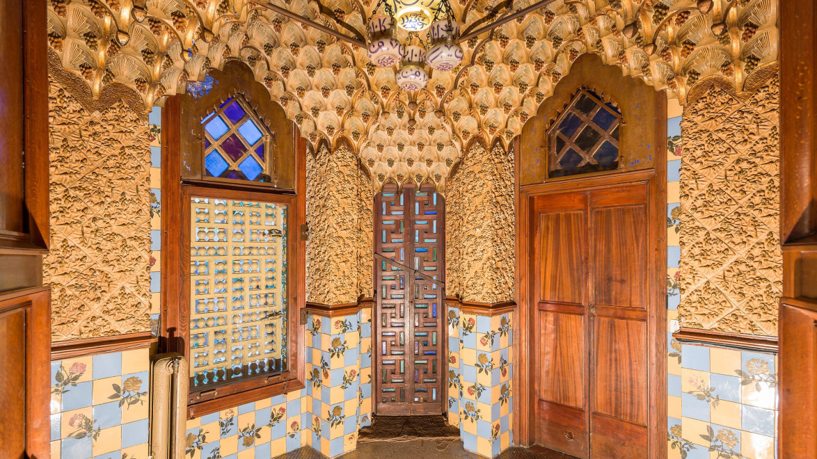 Intricately designed room with ornate walls, arched windows, and colorful tiles featuring floral patterns and geometric designs.