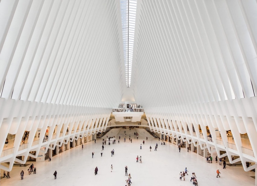 Spacious interior of Oculus transit hub with people walking under high ribbed ceiling and bright natural light.