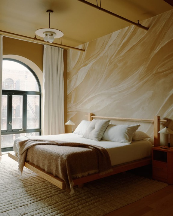 Cozy bedroom interior with natural tones, featuring a wooden bed, large arched window, and elegant wall design.