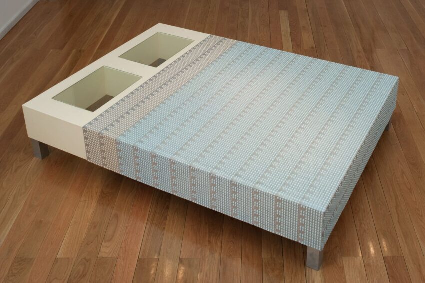 Modern coffee table with patterned surface and two recessed sections on a wooden floor.