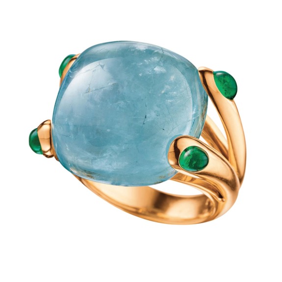 Gold ring with large blue gemstone and four small green gemstones on a white background.