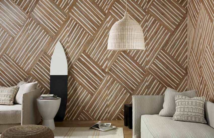 Modern living room with geometric wooden accent wall, light gray sofas, woven lamp, and decorative surfboard.