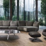 Modern living room with a large gray sectional sofa, a sleek coffee table, and a matching armchair with ottoman.