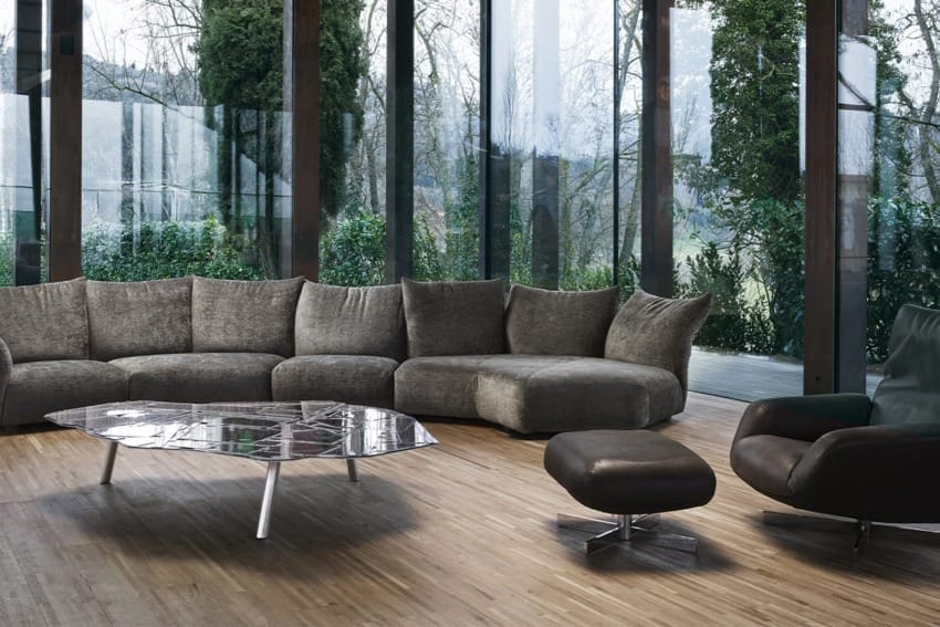 Modern living room with a large gray sectional sofa, a sleek coffee table, and a matching armchair with ottoman.