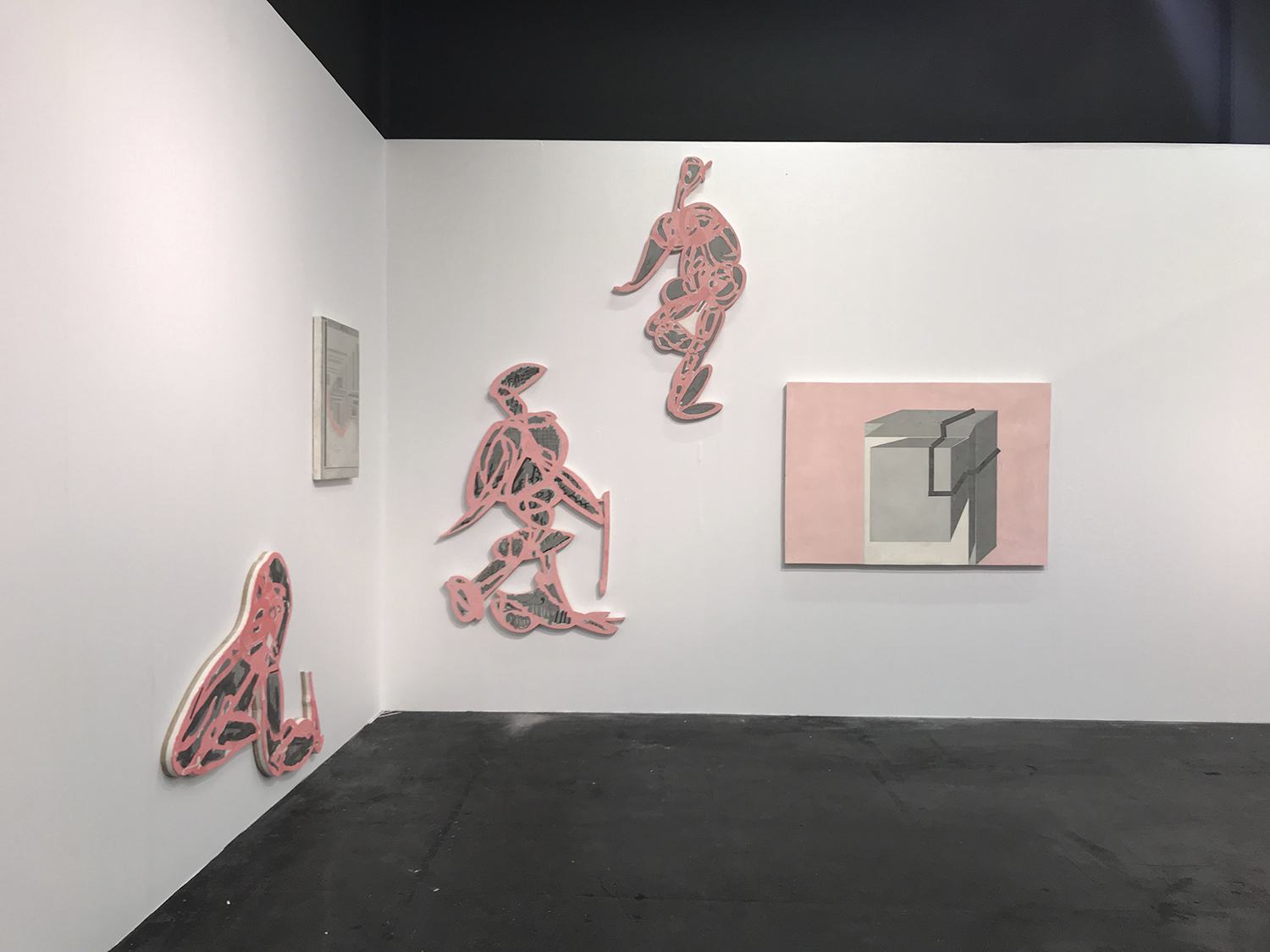 Art gallery wall featuring abstract pink sculptures and paintings with geometric and organic shapes on white and gray surfaces.
