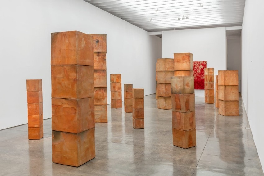 Contemporary art installation featuring stacked terracotta blocks in a minimalist gallery with bright lighting.