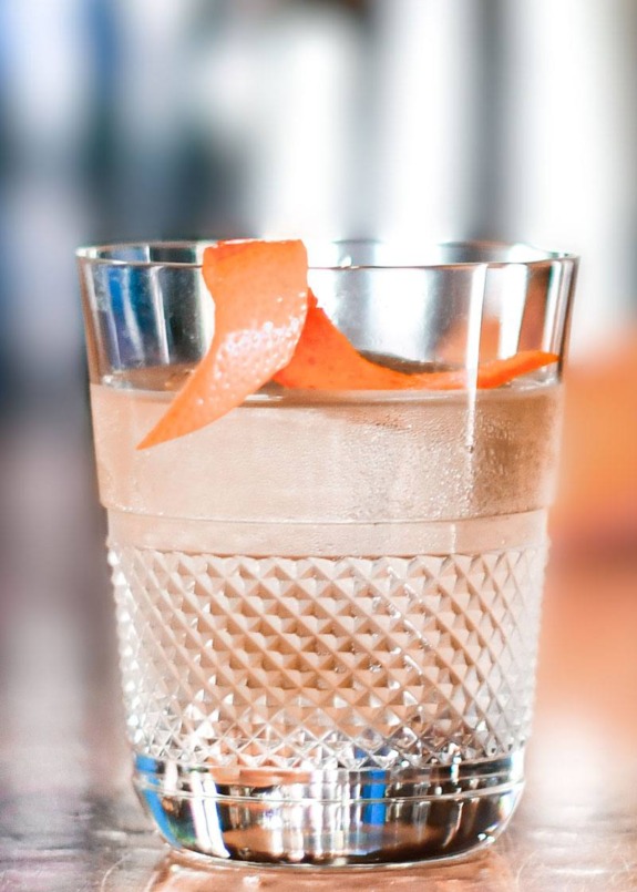 Cocktail in a textured glass garnished with a twist of orange peel.