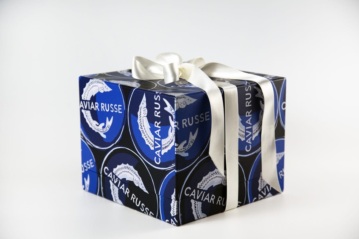 Gift box with Caviar Russe branding, wrapped in a dark blue design featuring a white ribbon bow on top.