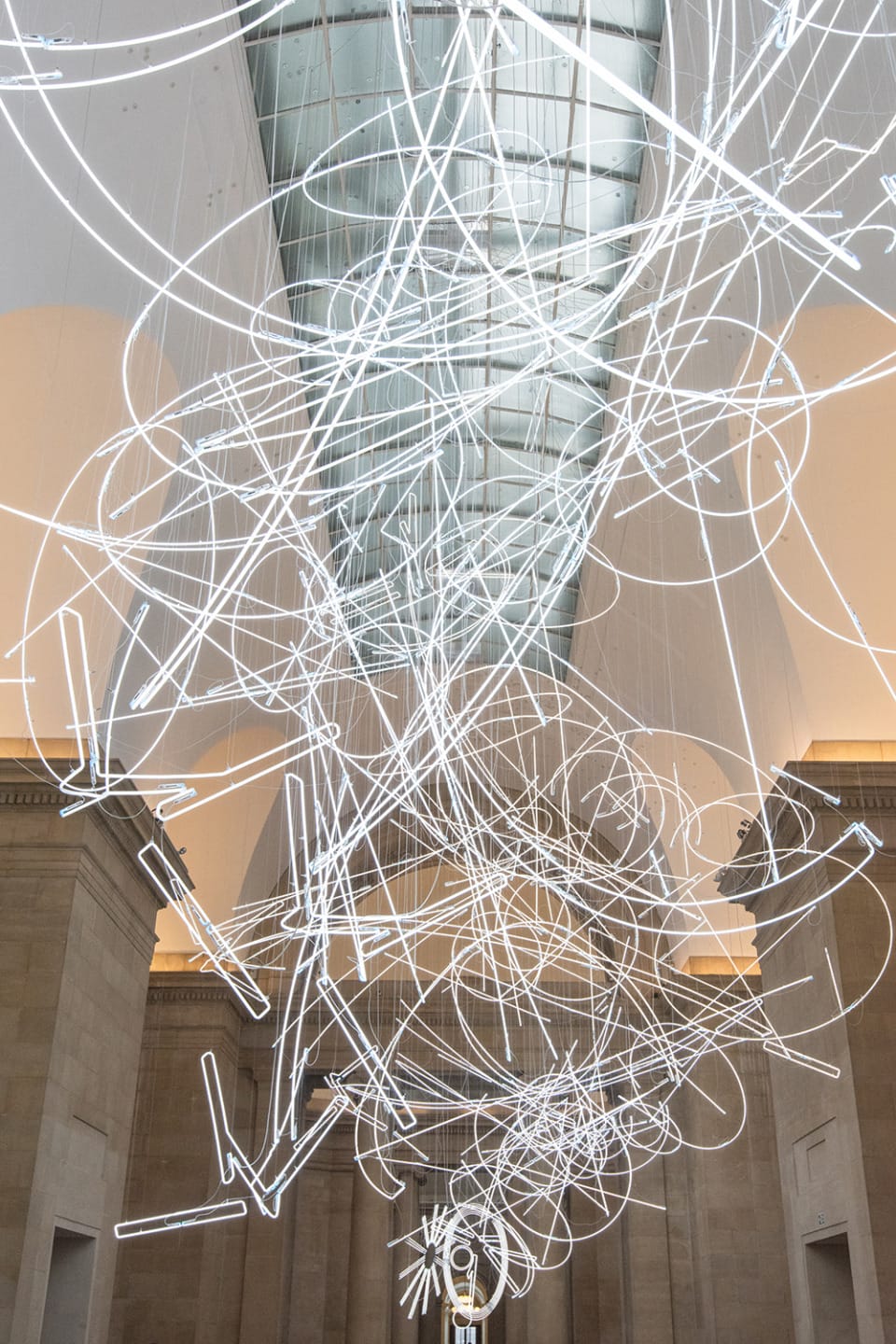 Abstract light installation with swirling white neon tubes in a modern architectural setting.