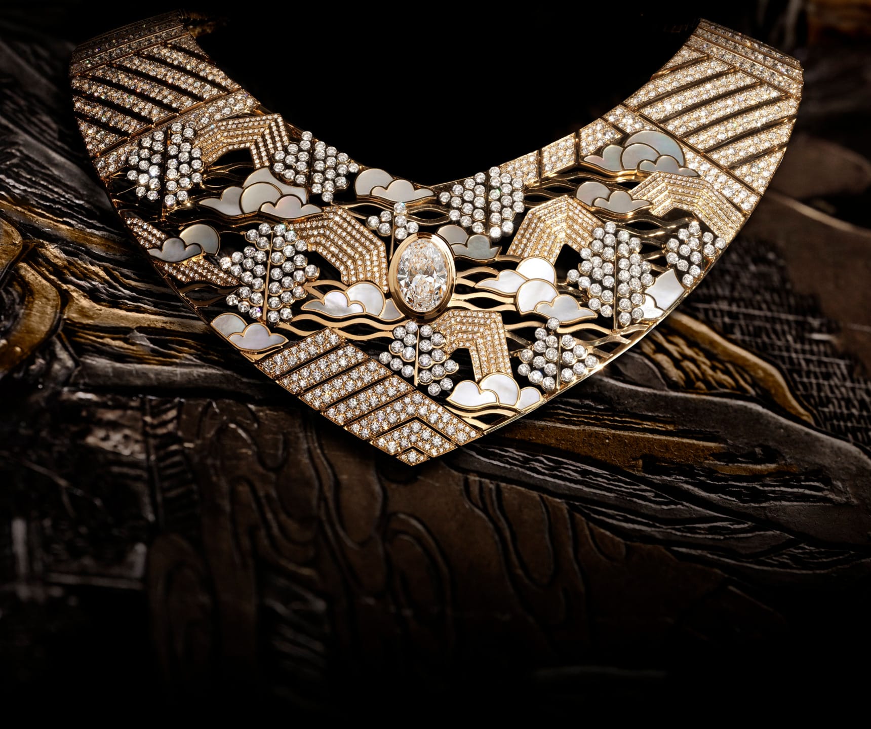 Elegant gold and diamond necklace with intricate cloud and pattern design on a dark, textured background.