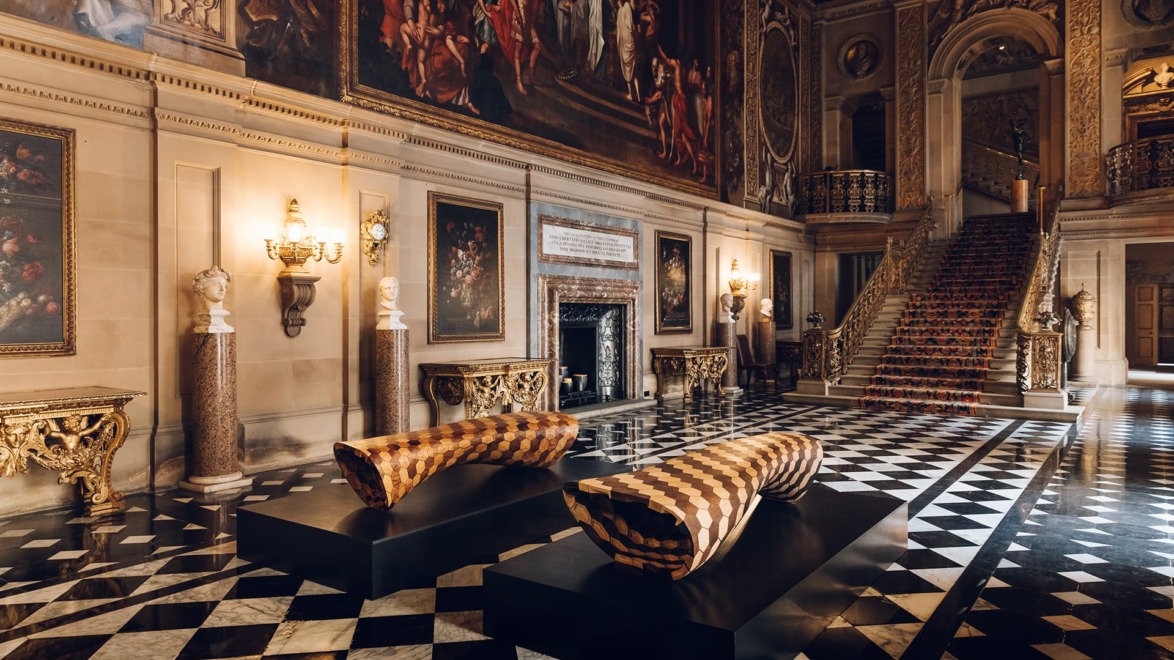 Opulent palace interior with checkered floor, grand staircase, ornate paintings, and luxurious patterned benches.