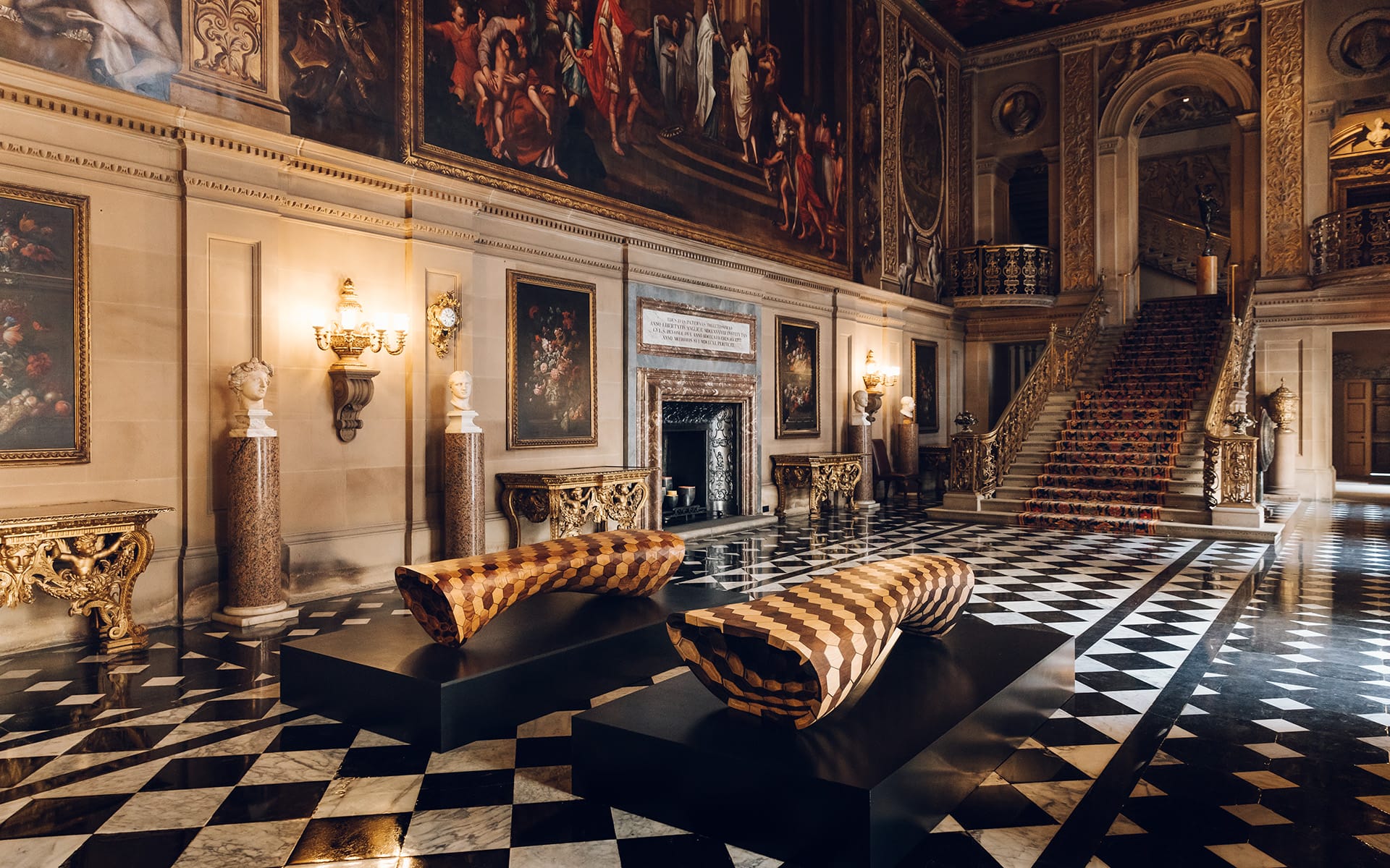 Opulent palace interior with checkered floor, grand staircase, ornate paintings, and luxurious patterned benches.