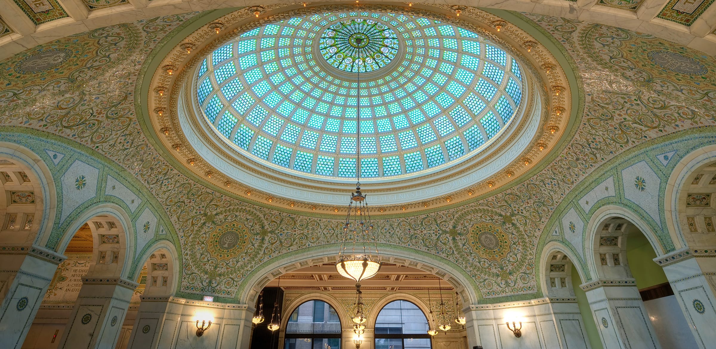 Stunning interior view of a grand hall with a large, intricate stained glass dome ceiling and ornate decorative details.