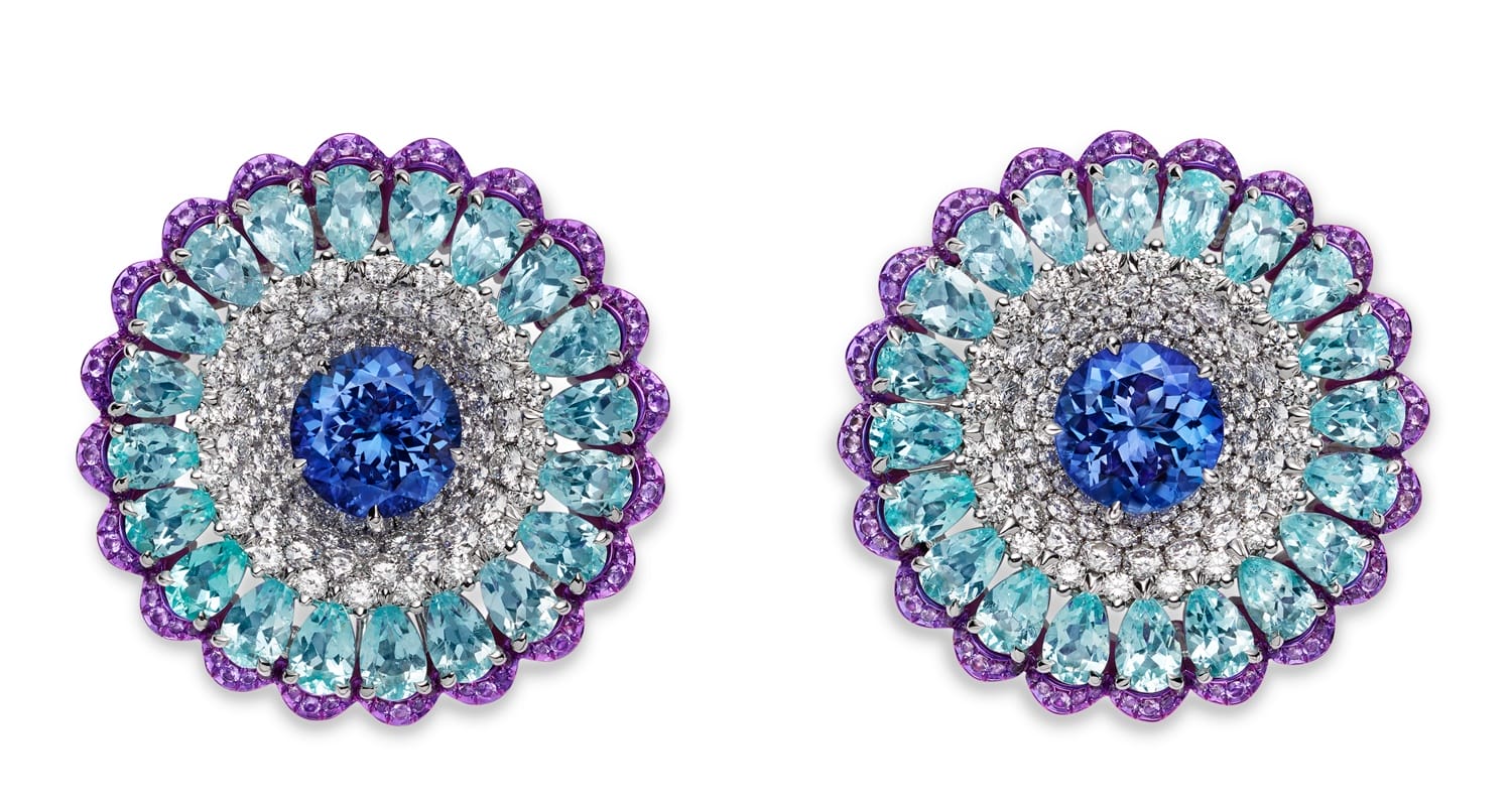 Colorful circular earrings with concentric layers of blue, teal, and purple gemstones around a central blue gemstone.