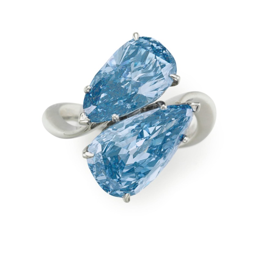 A white gold ring with two pear-shaped blue diamonds in a bypass design.