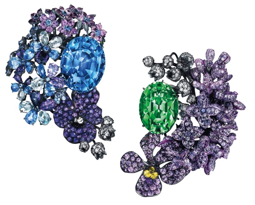Colorful floral jewelry with a large blue gemstone on the left and a large green gemstone on the right surrounded by smaller stones.