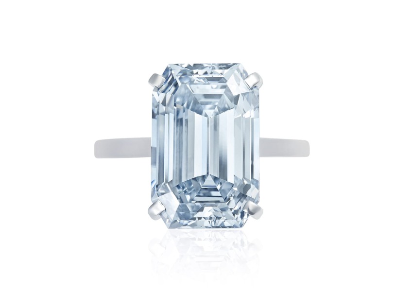Emerald-cut blue diamond ring with a sleek silver band on a white background.