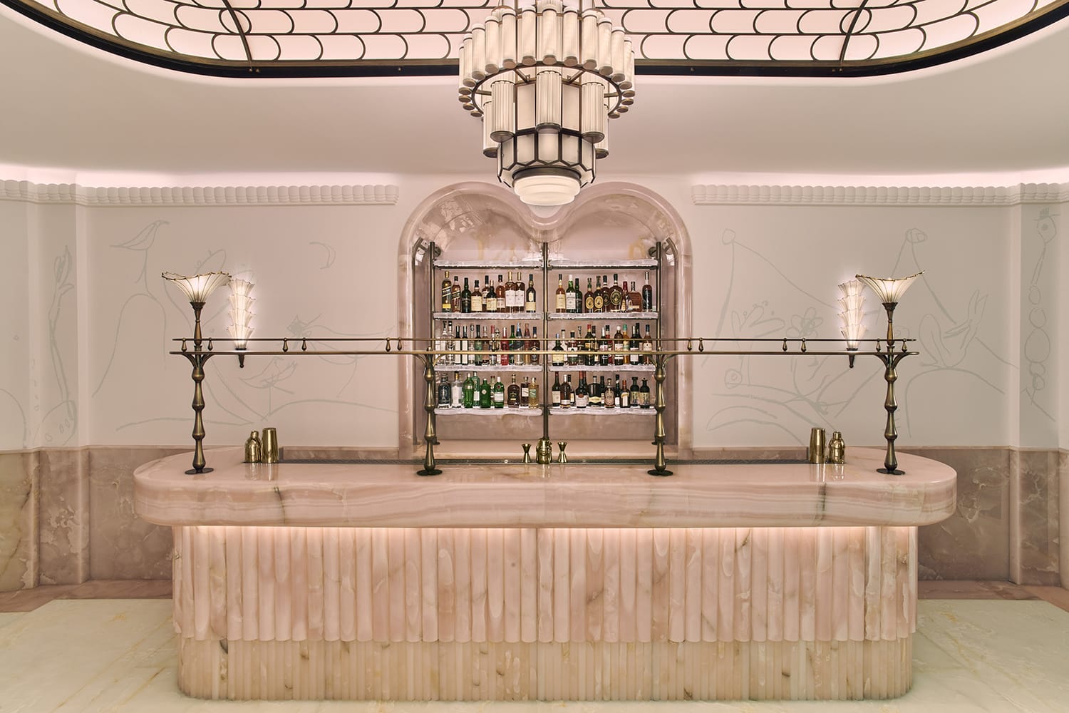 Art deco style bar with elegant lighting, a smooth marble countertop, and a variety of bottles on display.