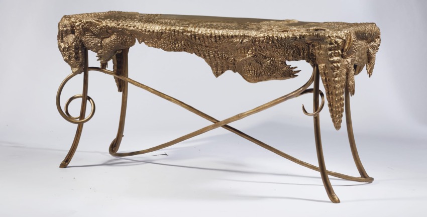 Gold sculptural table with intricate organic textures and unique twisted metal legs.
