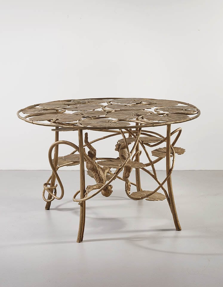 Artistic table with intricate, intertwined metalwork design featuring circular motifs against a plain background.