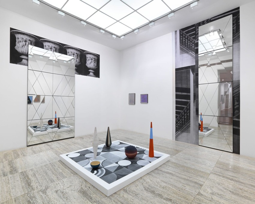 Modern art gallery with geometric sculptures, large mirrors, and minimalist wall art in a spacious, well-lit room.