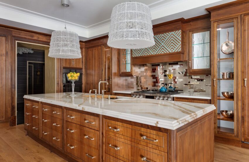Luxury kitchen with wooden cabinets, marble island, mosaic backsplash, and modern pendant lights.