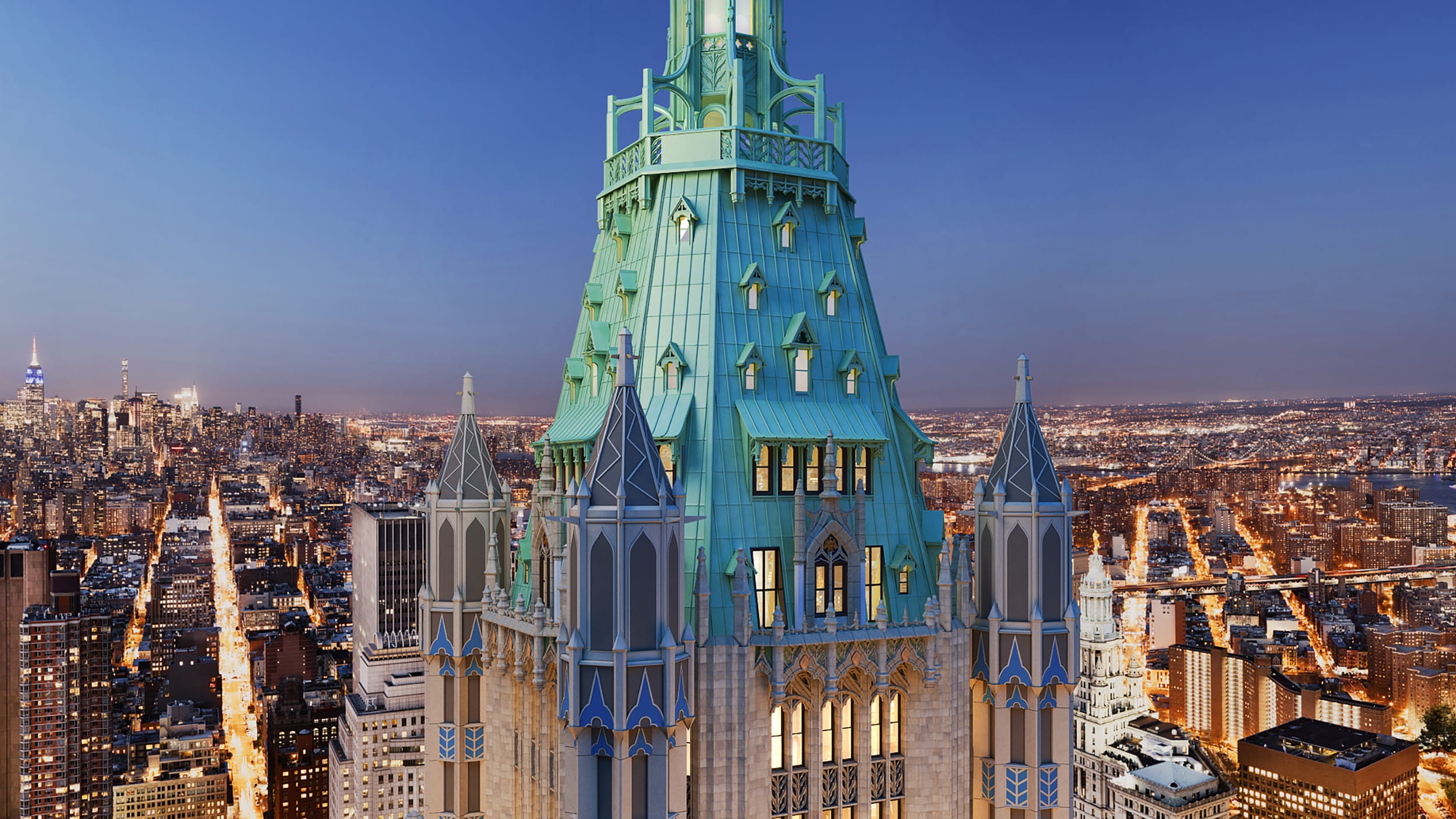 Woolworth Building's illuminated neo-Gothic top with New York City skyline at dusk in the background.