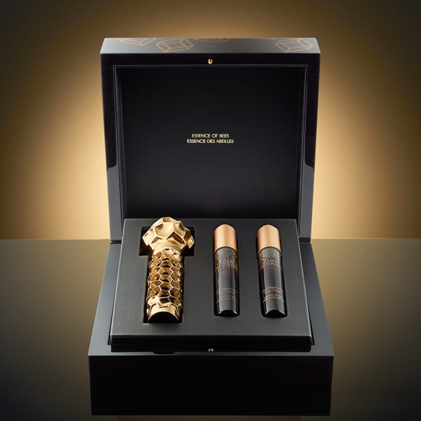 luxury perfume set in an elegant black and gold box with intricate bottle designs placed on a reflective surface