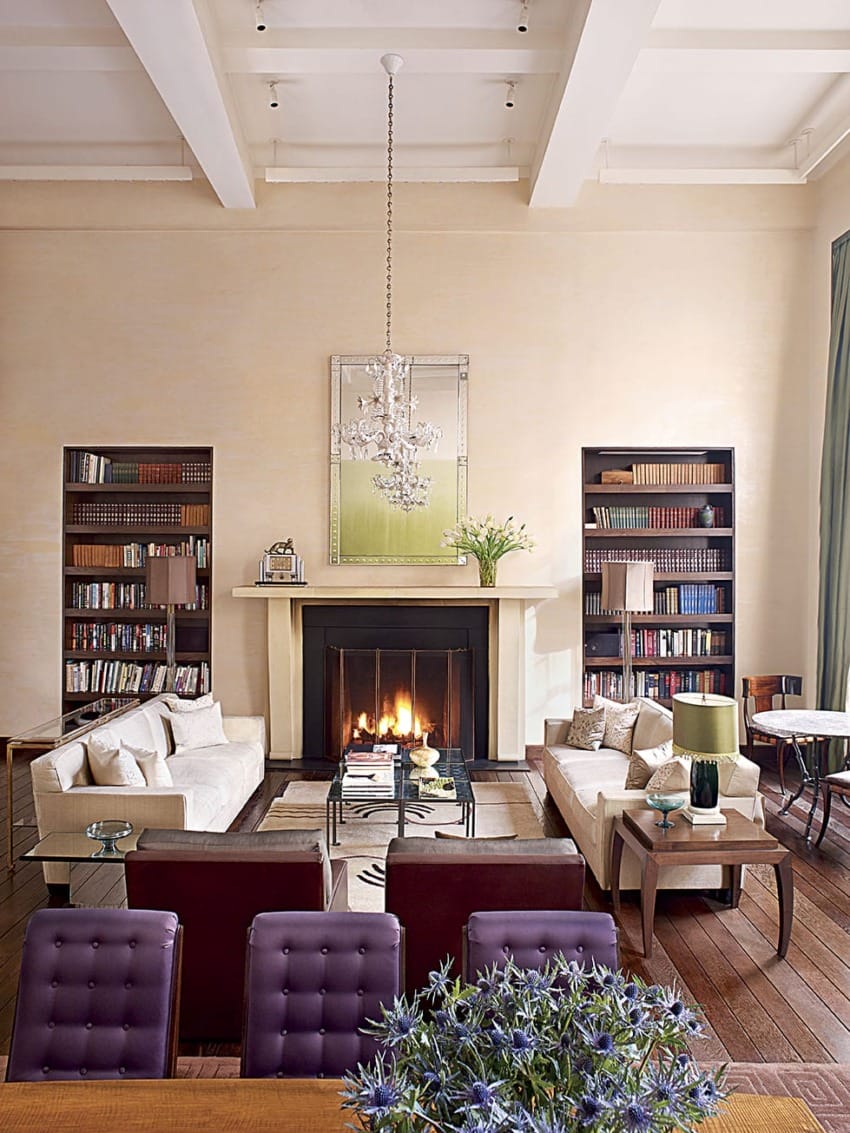 Spacious living room with elegant furniture, bookshelves, a cozy fireplace, and a chandelier centered above.