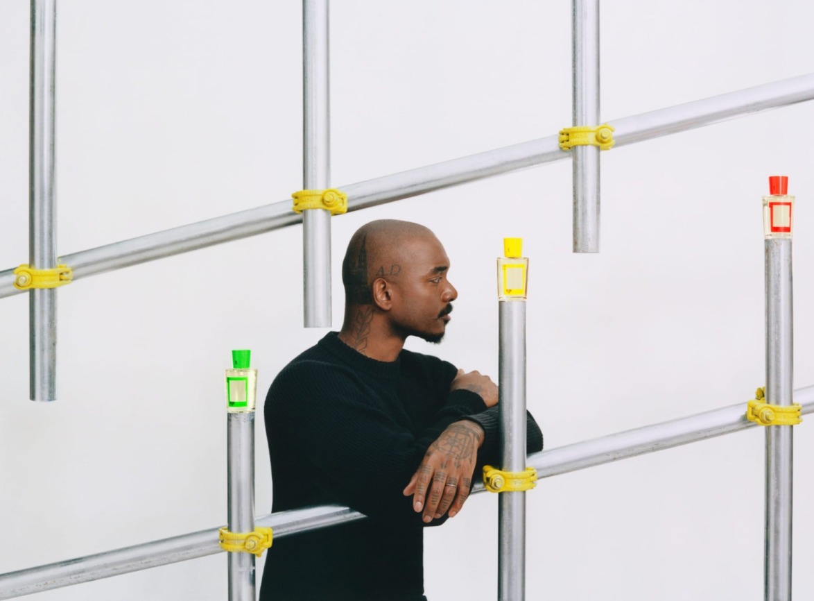 Man in black sweater leaning on metal bars with colorful clamps