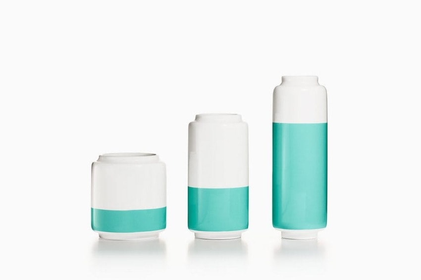 Three decorative vases with a white and teal color scheme, varying in height, on a plain background.