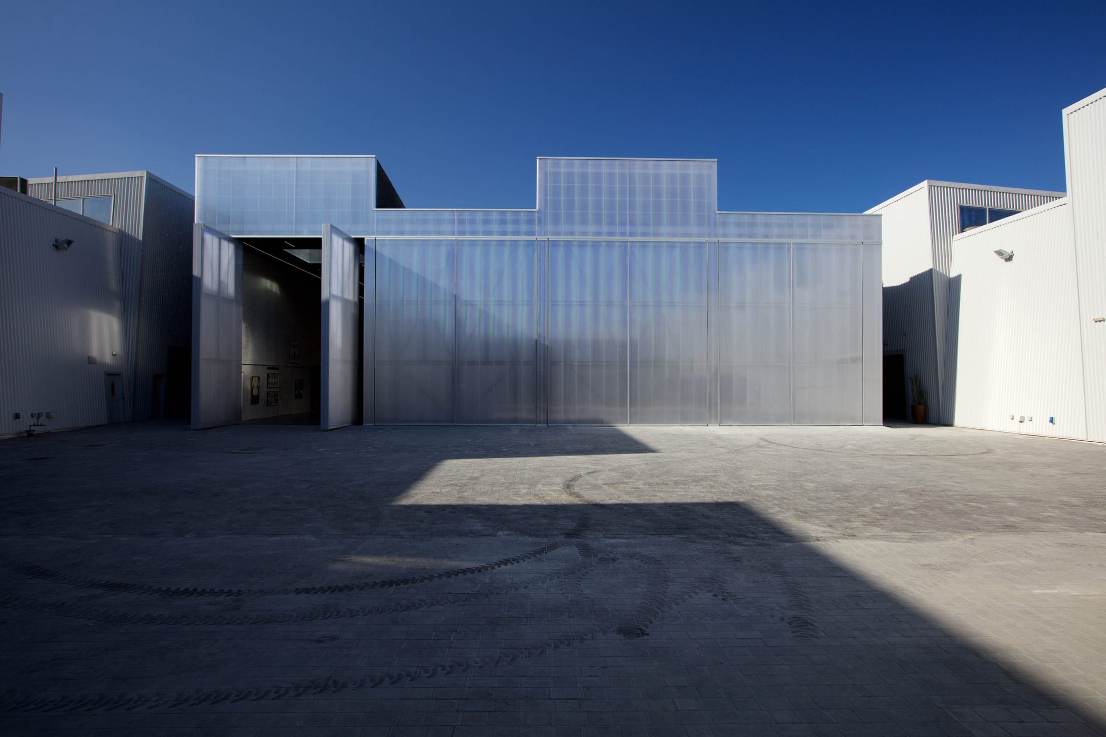 Modern industrial building with large reflective facade under a clear blue sky. Minimalist architectural style.