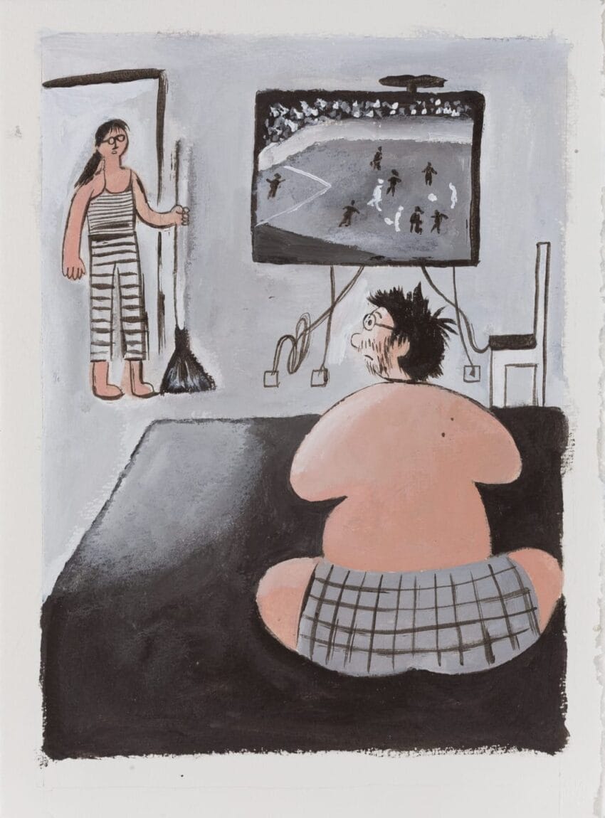 Person watching football on TV while sitting on floor, another person with broom standing in background, both wearing casual clothes.